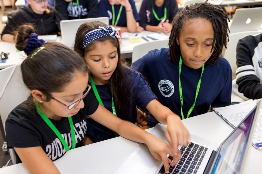 Three young girls sitting in front of a laptop.